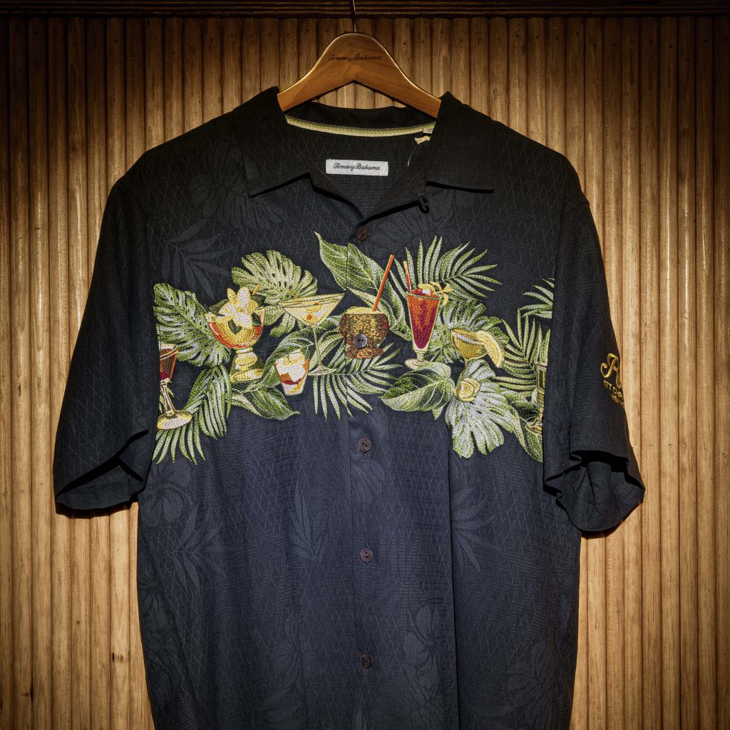 A black short sleeved button shirt with fruit graphics on the front