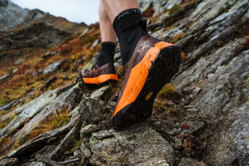 close up of feet in trail running shoes hiking up a rocky slope