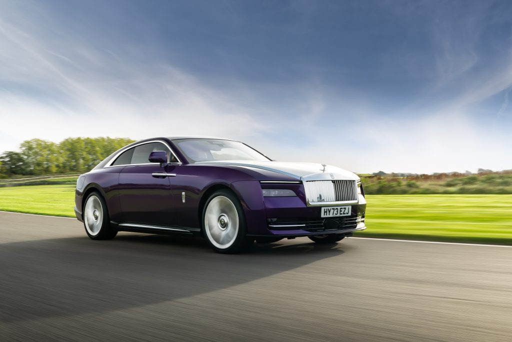 Purple Rolls Royce Spectre driving past a field