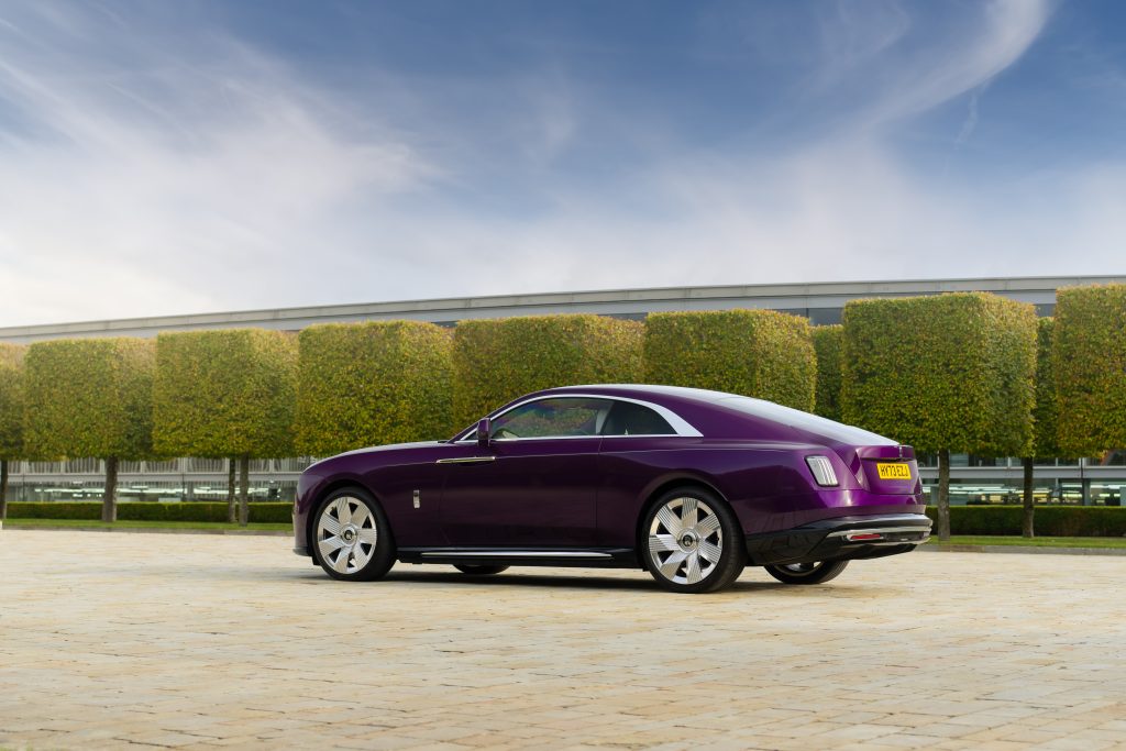 exterior rear 3/4 view of a purple Spectre parked in front of a row of cubed hedges