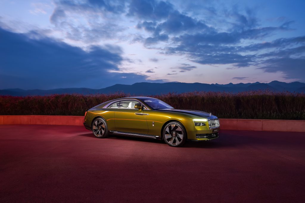 olive green Rolls Royce Spectre at sunset with mountains in the background