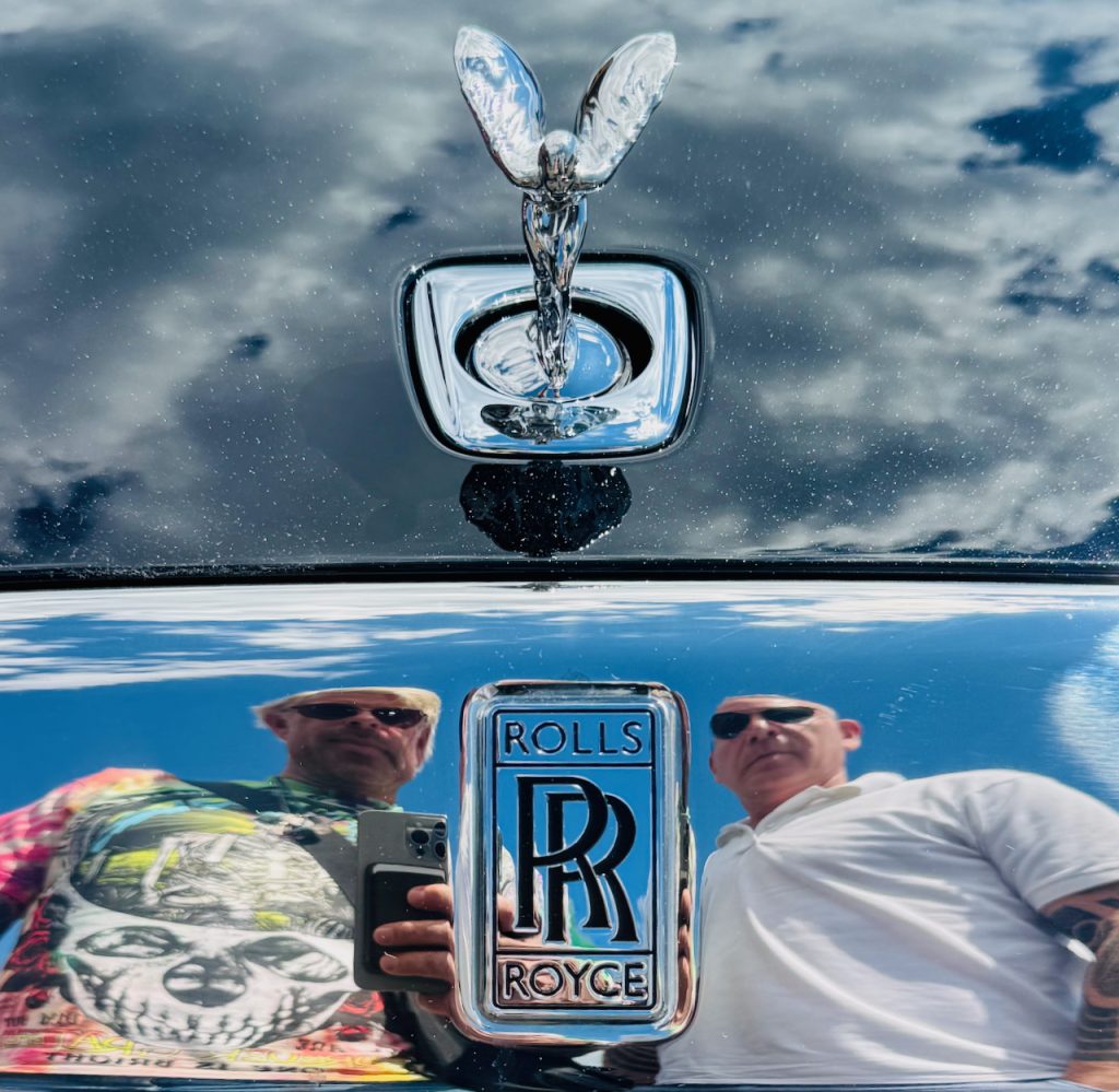 Rolls Royce badge and Spirit of Ectasy hood ornament with Josh Rubin and Evan Orensten reflected in chrome