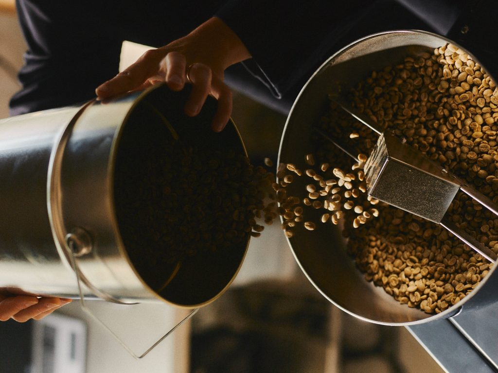 A person is pouring beans into a roaster