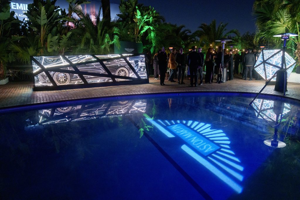 Artist Anthony James wrapped an Aston Martin Vanquish car in glass and metal box with lighting. Here it sits next to a reflective pool at night