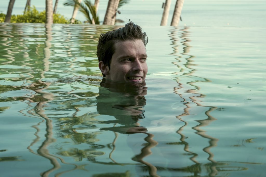 Patrick Schwarzenegger swimming in a pool with a view of the ocean